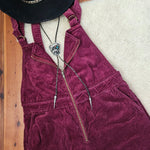 Maroon corduroy jacket with a black hat on a wooden surface