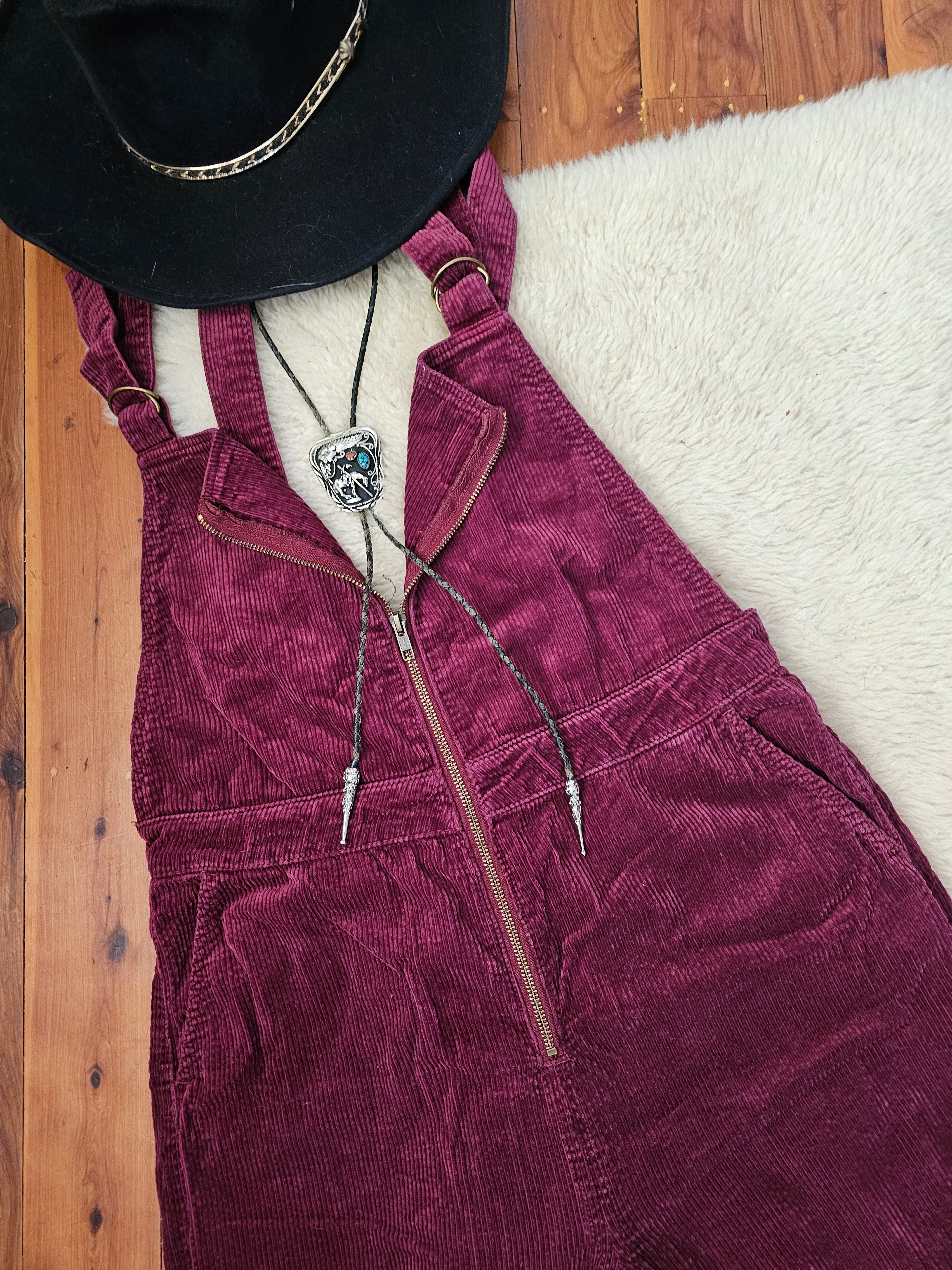 Maroon corduroy jacket with a black hat on a wooden surface
