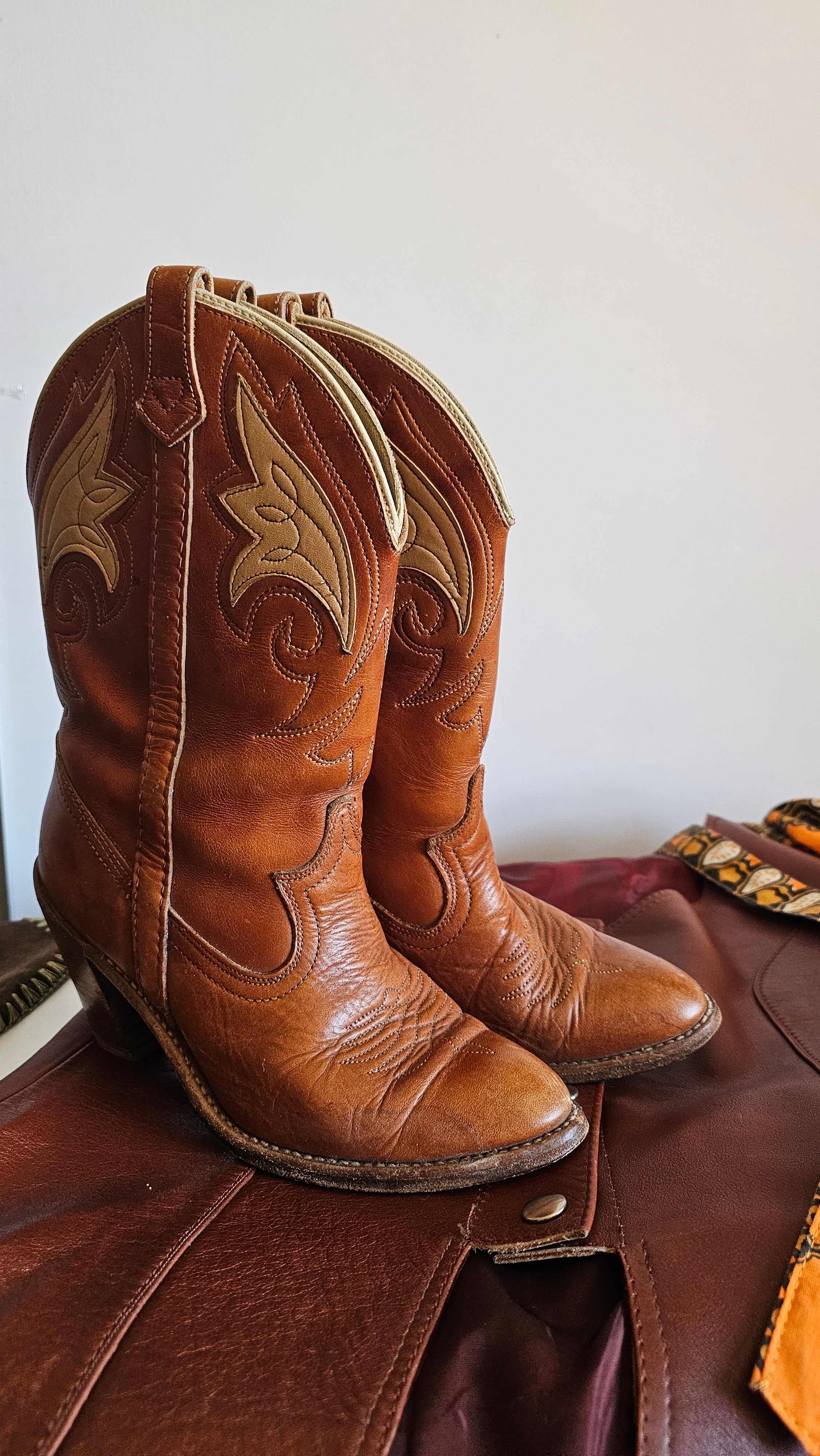 Close-up of brown leather cowboy boots with intricate designs on a white background