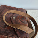 Brown leather bag with intricate patterns on a textured surface