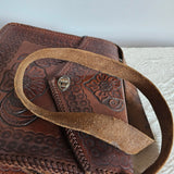 Brown leather bag with intricate patterns on a textured surface