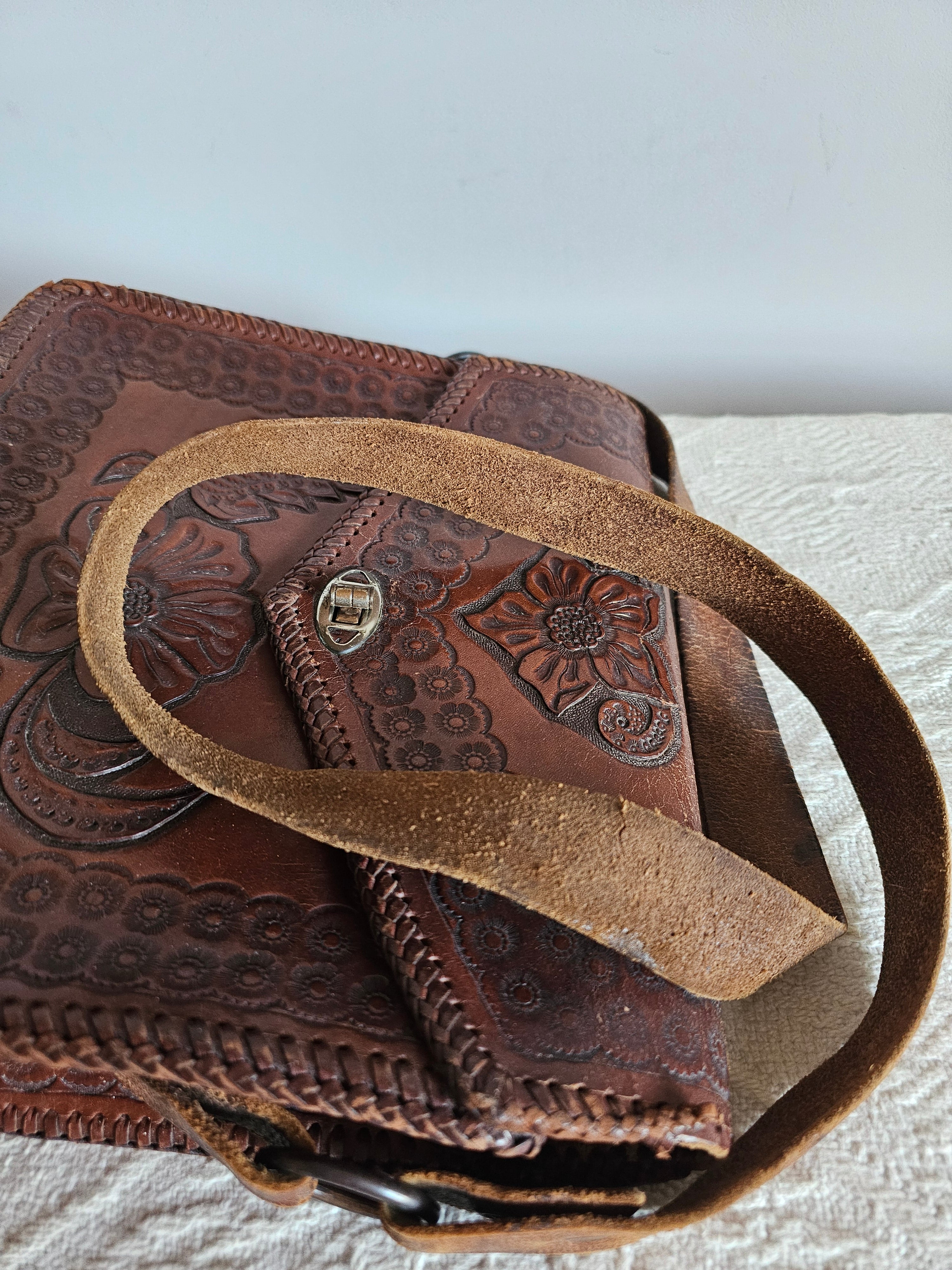 Brown leather bag with intricate patterns on a textured surface