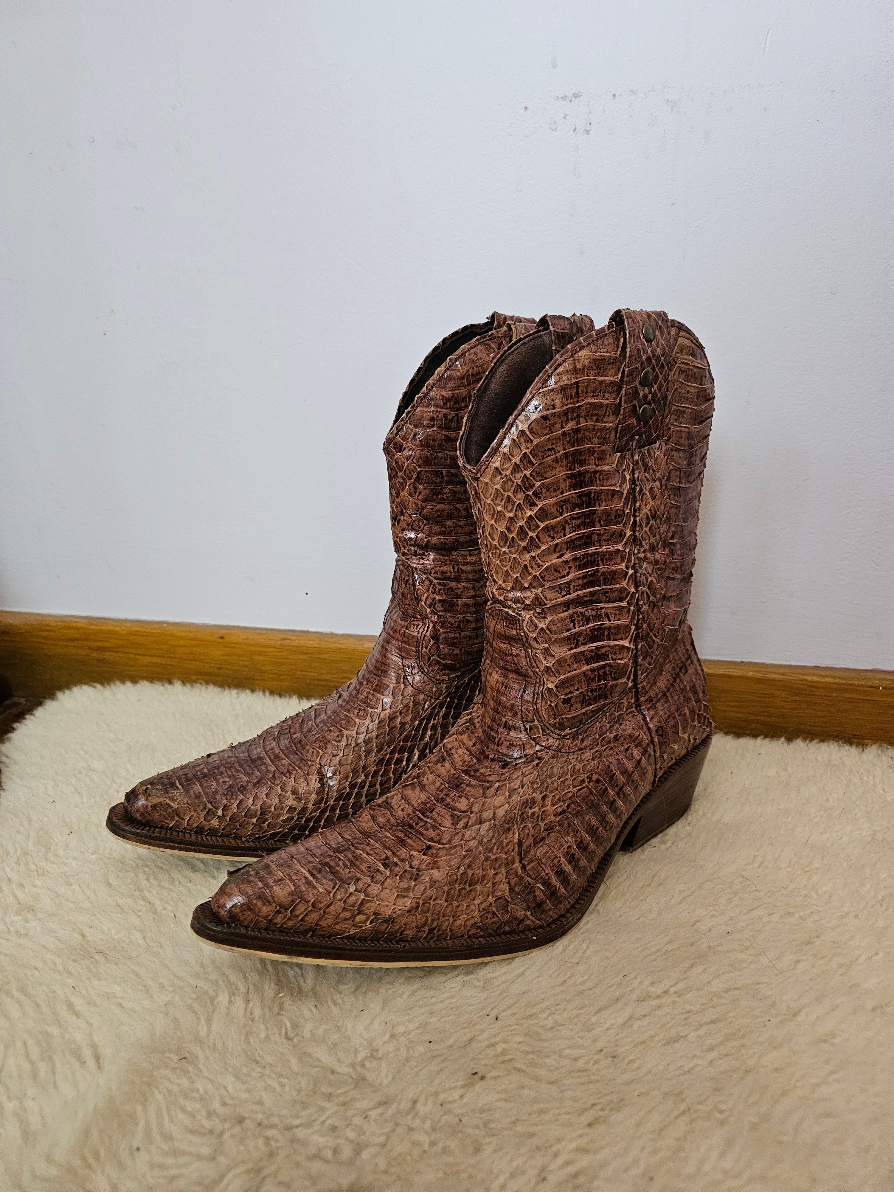 Brown leather boot with decorative pattern on a white wall