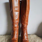 Pair of brown leather knee-high boots on a light background