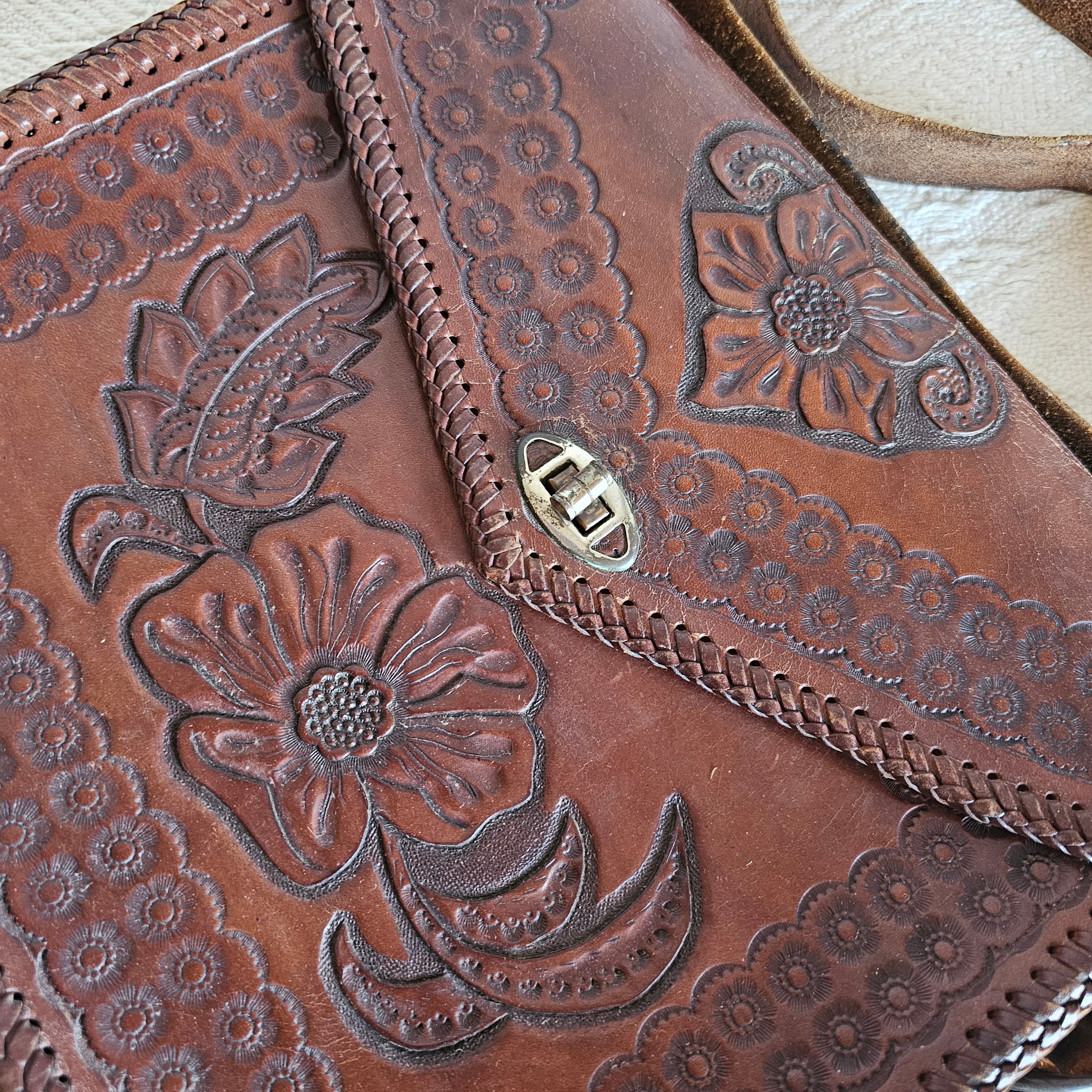 Brown leather bag with floral embossing on a light background