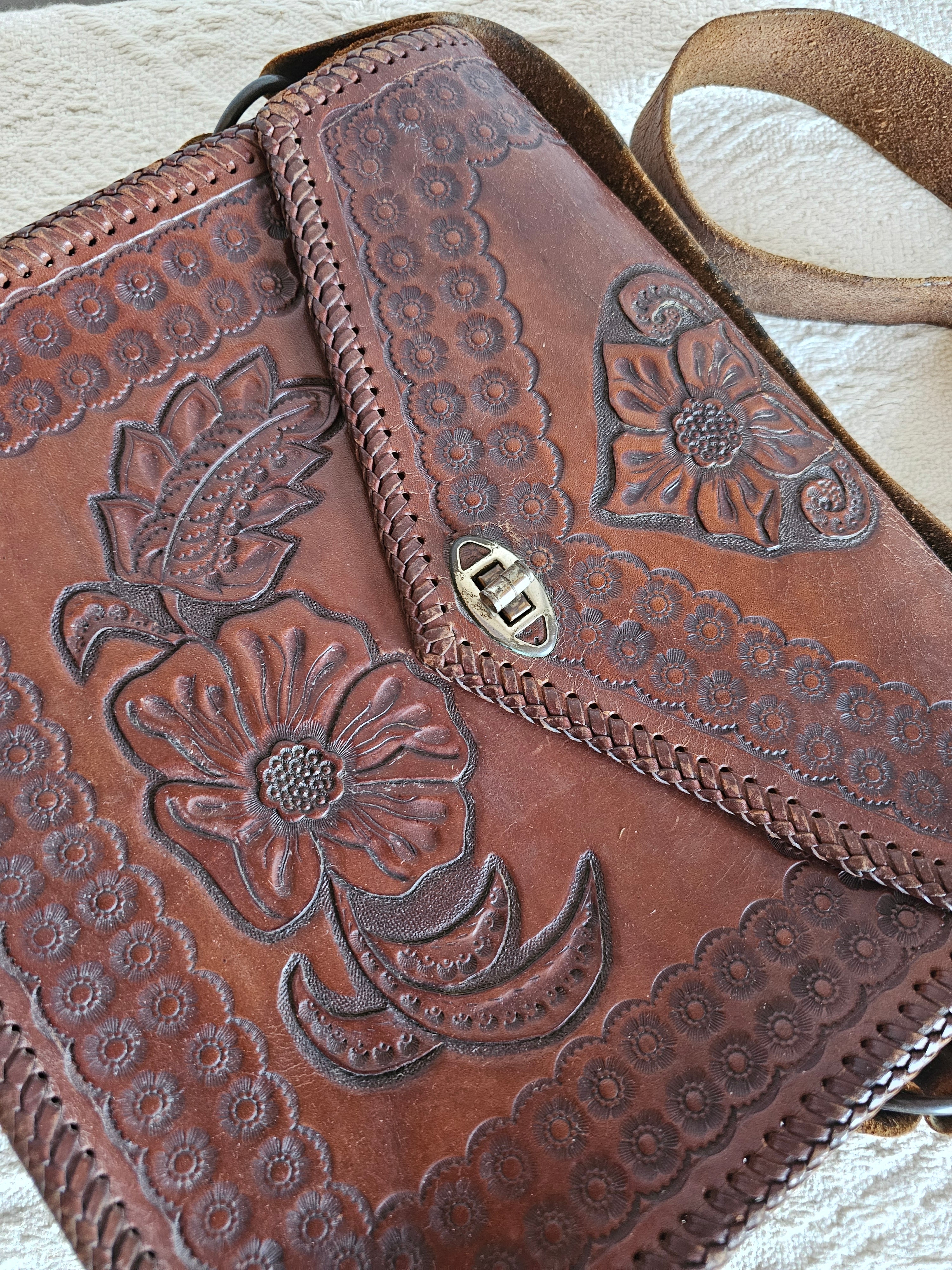 Brown leather bag with floral embossing on a light background