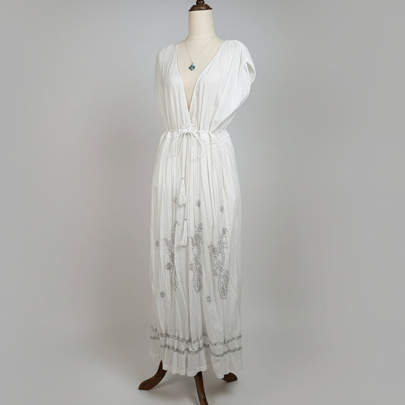 White dress with silver embellishments on a mannequin against a gray background