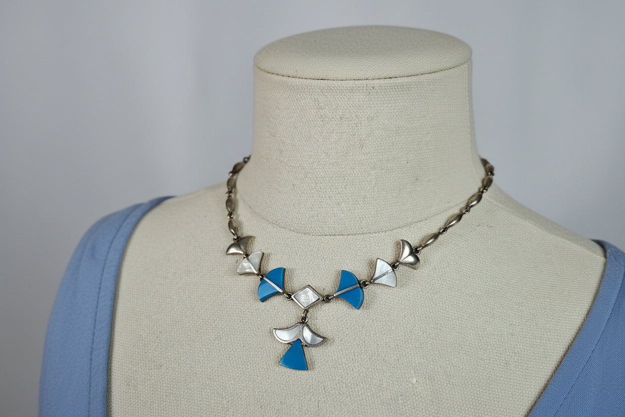 A sterling silver necklace with inlaid turquoise and mother of pearl displayed on a mannequin bust
