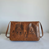 Brown leather wallet with snake skin pattern on a white background