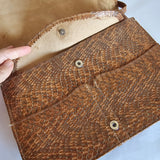 Brown leather clutch with snake skin pattern on a light blue background