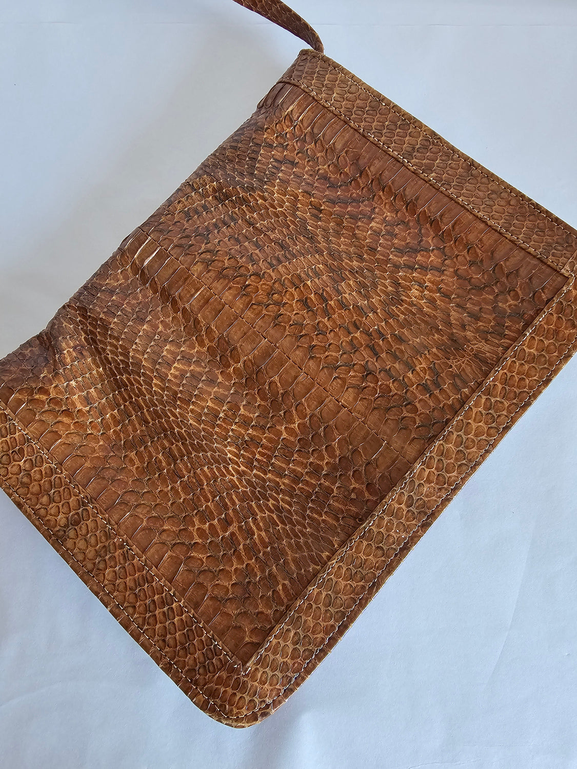 Brown textured leather clutch bag on a light gray background