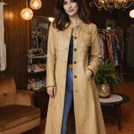 Woman wearing a beige coat in a clothing store with wooden walls and hanging lights.