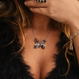 Close-up of a person wearing a butterfly necklace and ring with a fur garment.