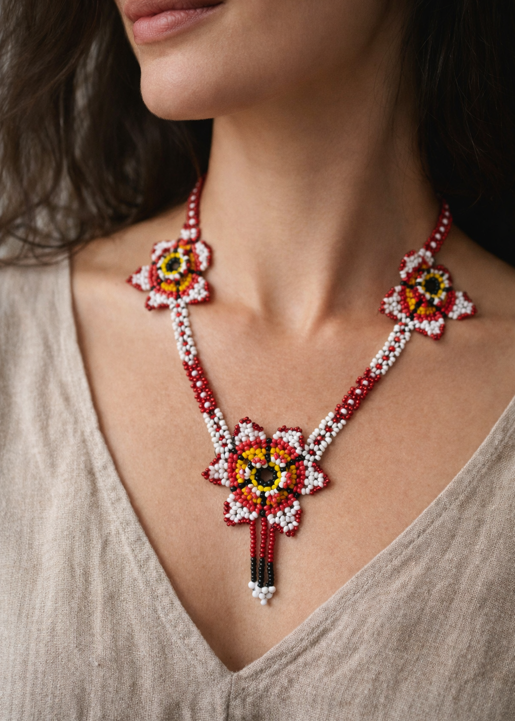 Close-up of a woman wearing a colorful beaded necklace with a neutral background