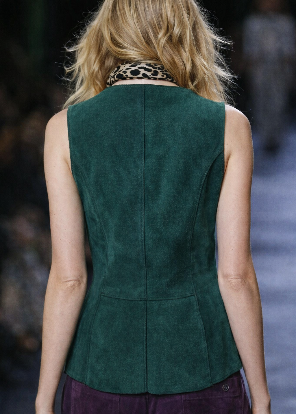Person wearing a green suede vest on a runway