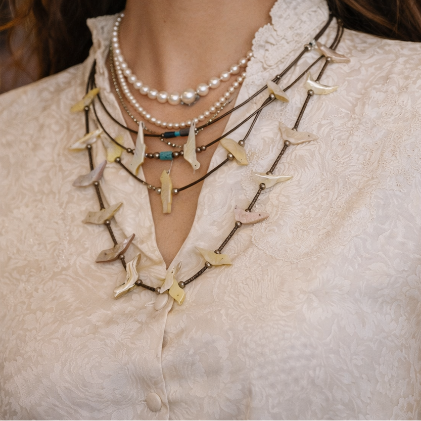 Woman wearing a layered necklace with starfish designs and pearl earrings.