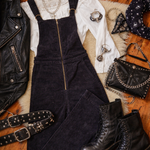 Black overalls, boots, jacket, and accessories on a wooden floor.