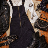 Black overalls, boots, jacket, and accessories on a wooden floor.