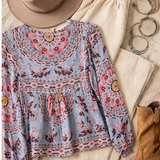 Floral blouse with a hat, boots, and jewelry on a textured surface