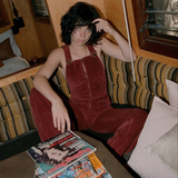Person wearing red velvet overalls sitting on a couch with a magazine in front