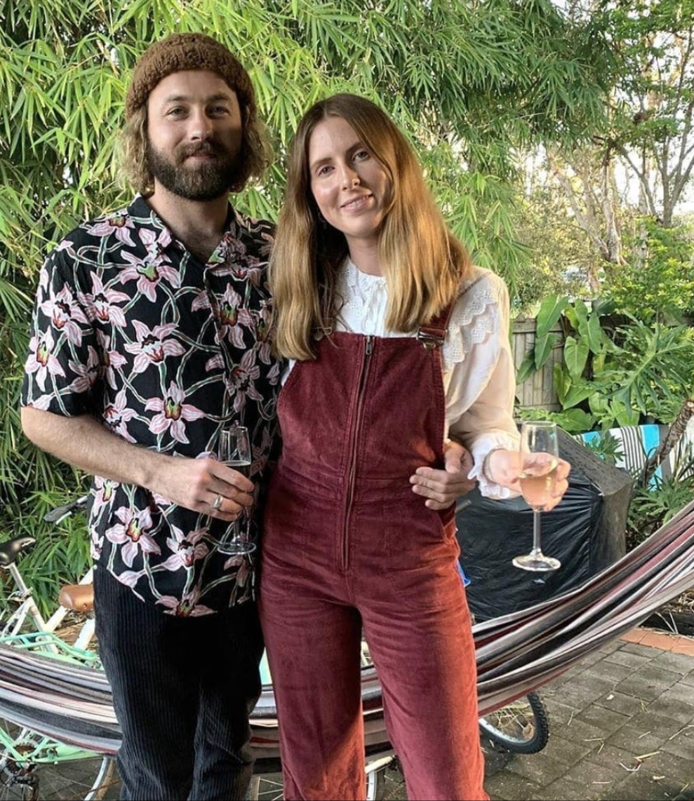 Two people standing together in a garden setting, holding drinks.