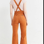 Person wearing brown corduroy overalls on a white background