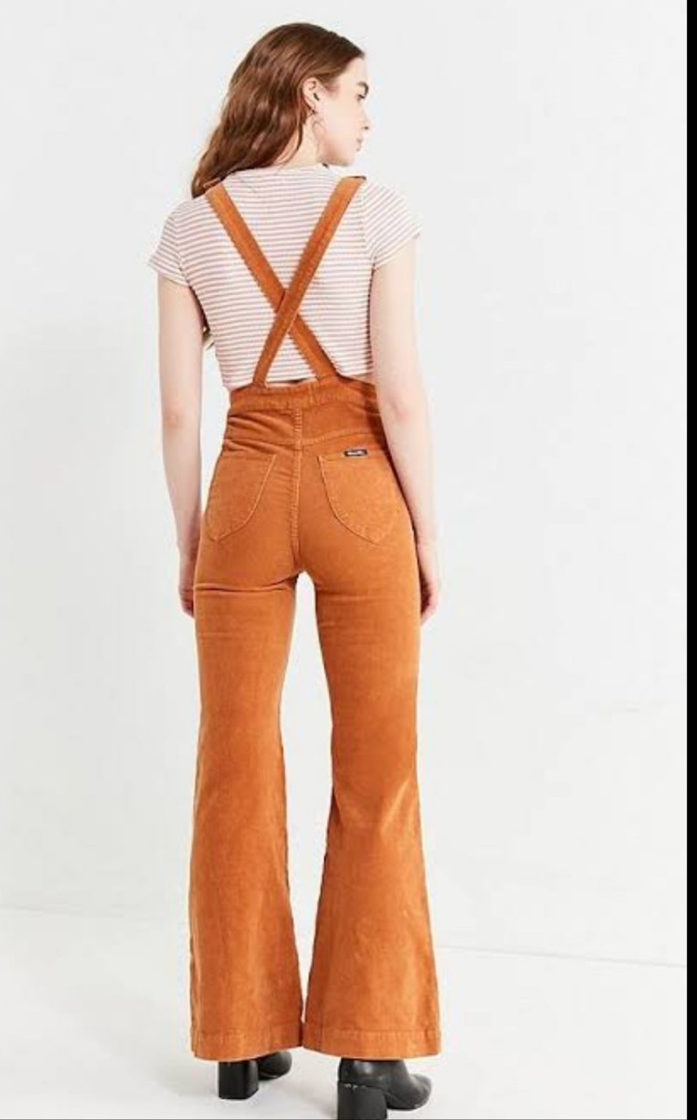 Person wearing brown corduroy overalls on a white background