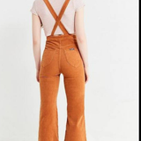 Person wearing brown corduroy overalls on a white background