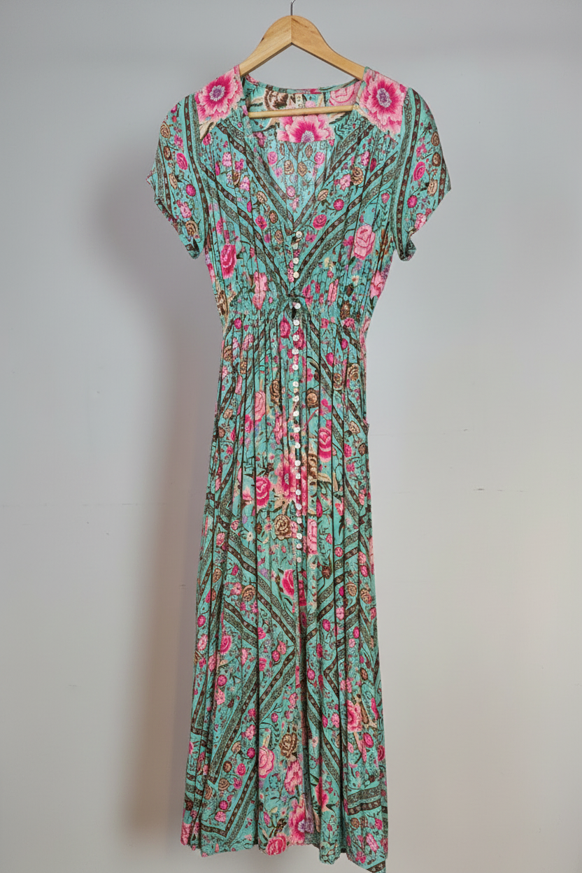 Floral dress with pink flowers on a hanger against a white wall.