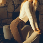 Model wearing Rolla’s Dusters Bootcut cords in Tobacco, size 30, styled with a ribbed top in a cozy indoor setting.