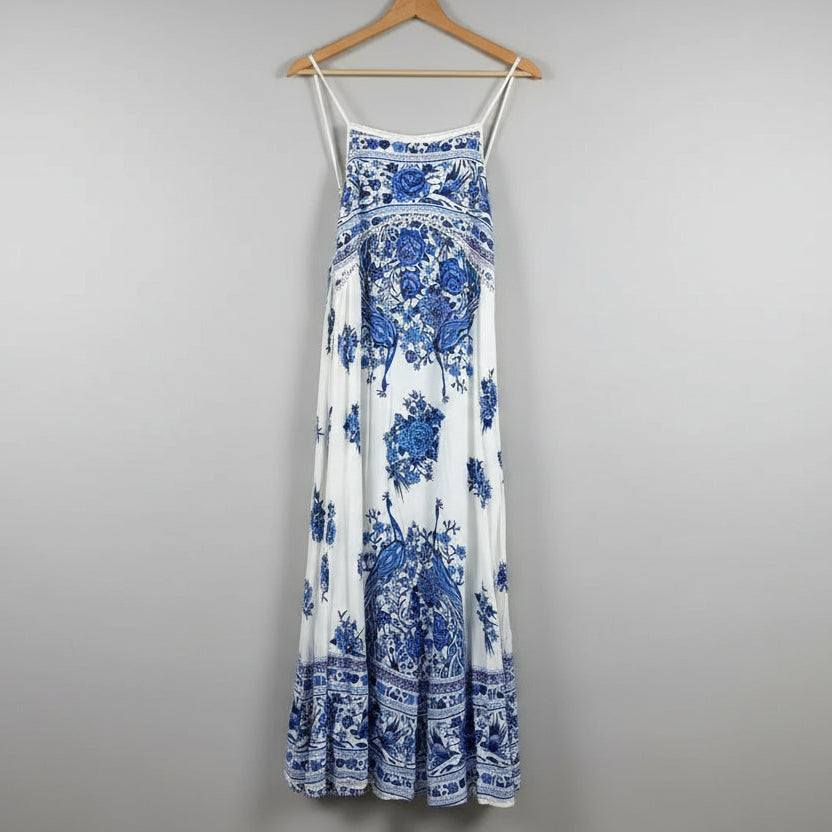 Blue and white floral dress hanging on a wooden hanger against a plain wall.