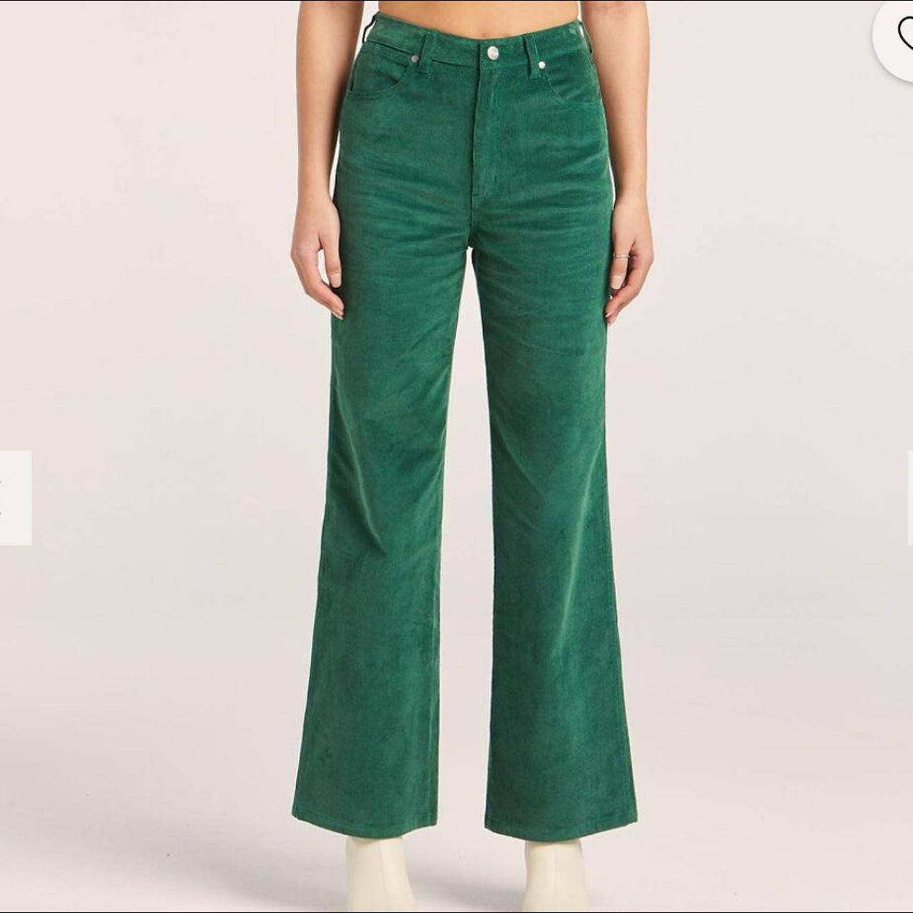 Green corduroy pants worn by a person on a light gray background