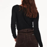 Person wearing brown flared jeans and a black top on a white background