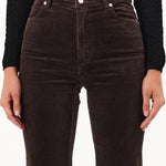 Brown flared jeans worn by a person on a white background