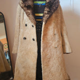 Beige coat with fur trim on a mannequin against a neutral wall.