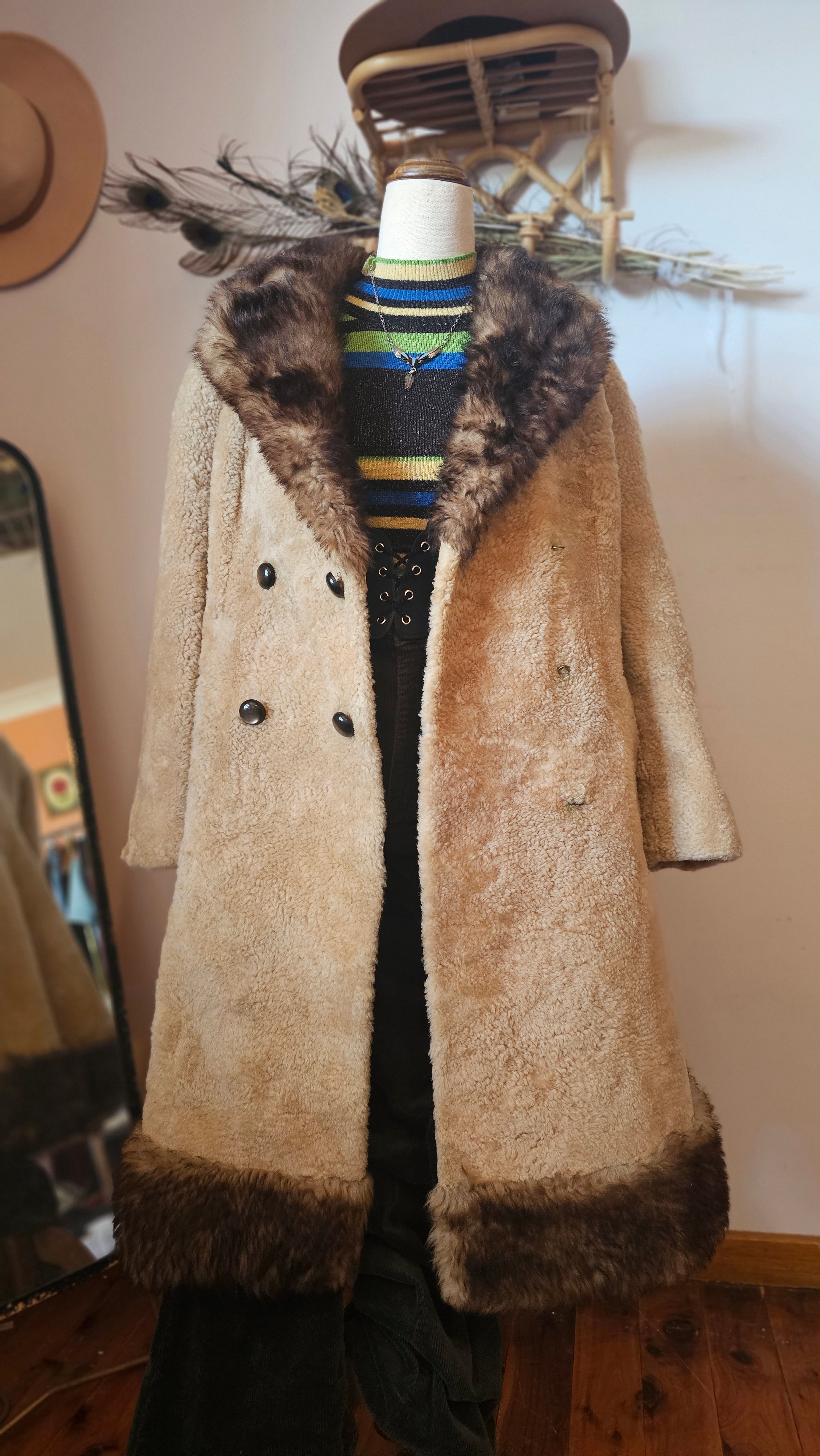 Beige coat with fur trim on a mannequin against a neutral wall.