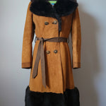 Brown coat with black fur trim on a mannequin against a white wall.