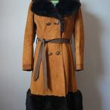 Brown coat with black fur trim on a mannequin against a white wall.