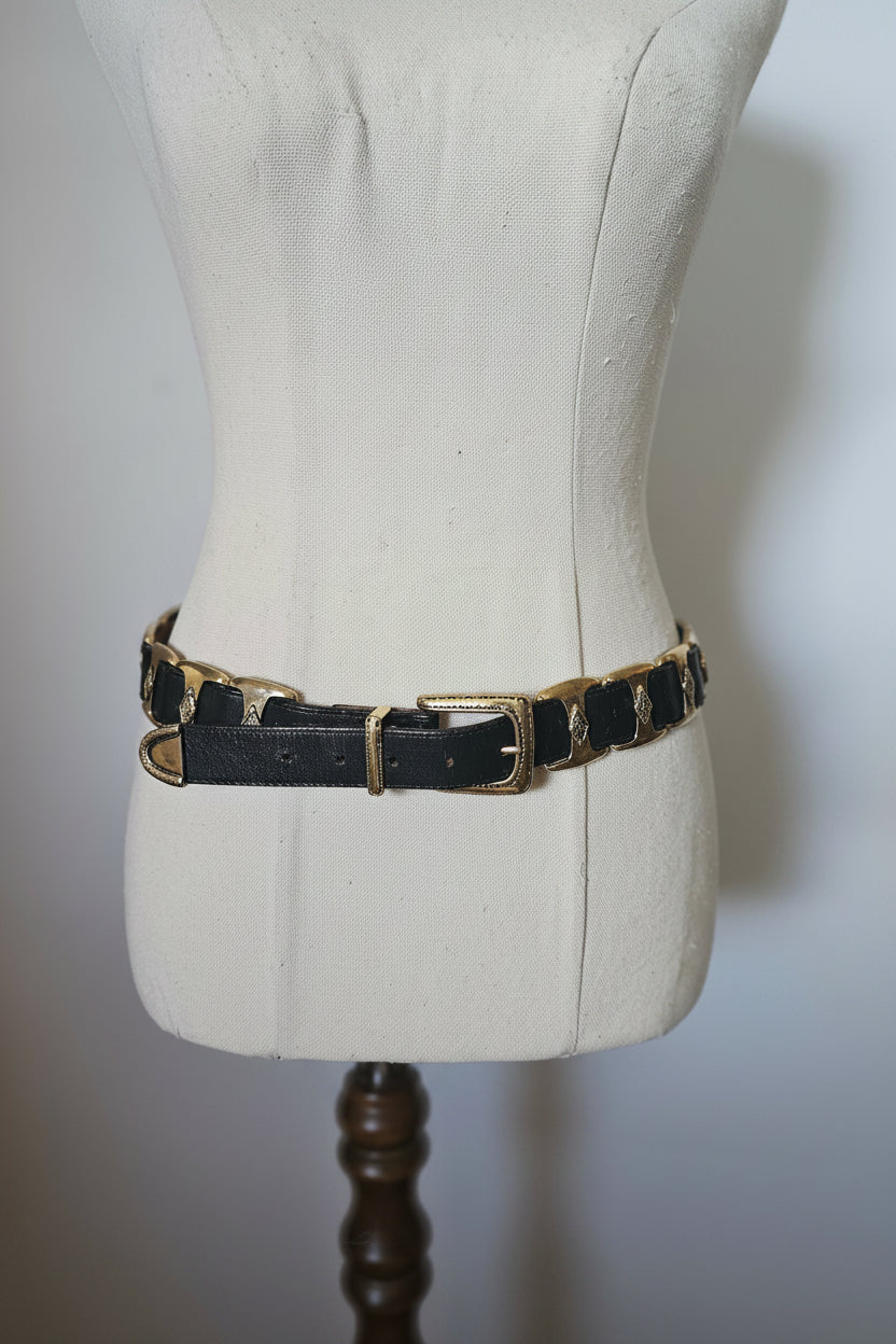 Black leather bracelet with gold accents on a mannequin arm against a neutral background