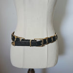 Black leather bracelet with gold accents on a mannequin arm against a neutral background