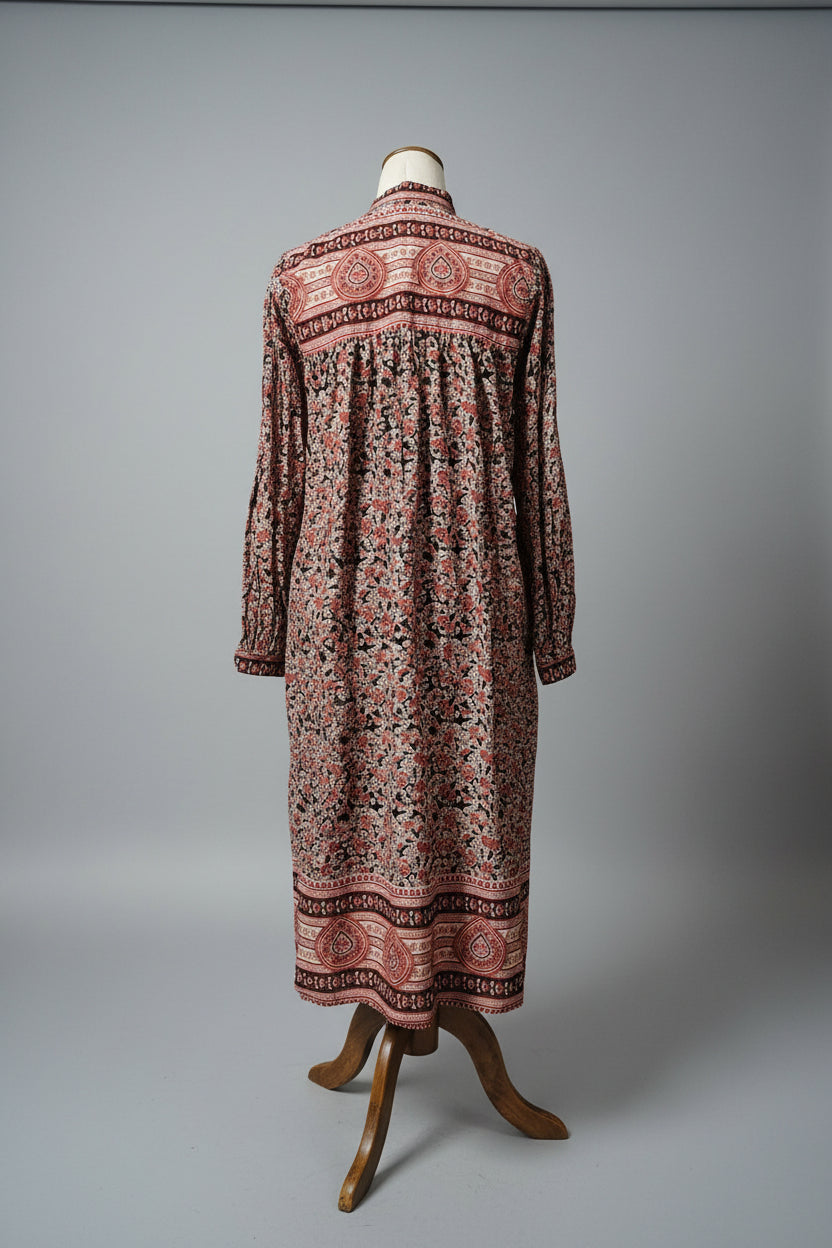 Long patterned dress on a mannequin against a plain wall.