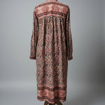 Long patterned dress on a mannequin against a plain wall.