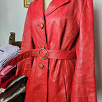 Side angle of 70s Stewart Hunt red leather trench coat emphasizing belt detail, button accents, and textured leather finish.