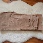 Folded Rolla’s Dusters Bootcut cords in Tobacco, size 30, displayed on a white fur rug, showing corduroy texture and back pocket label.
