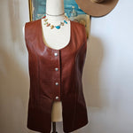 Brown leather saddle on a stand with a hat and decorative item in the background.