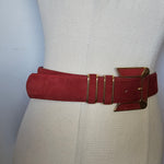 Red belt with gold buckle on a beige cushion against a light background