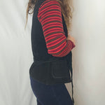 Person wearing a black coat, red striped shirt, and brown hat on a white background