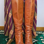 Pair of brown leather knee-high boots on a patterned surface