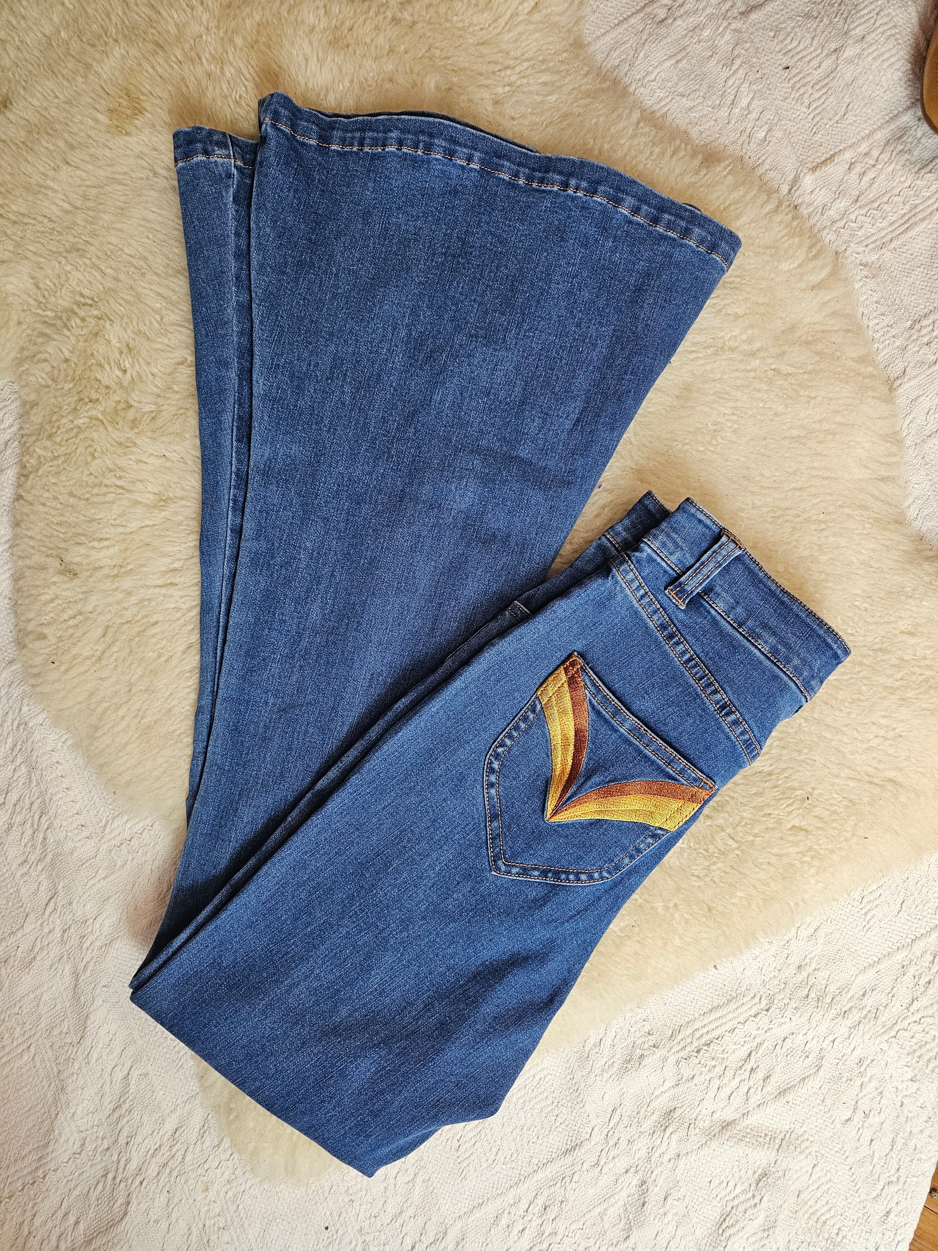 Folded blue jeans on a textured beige surface