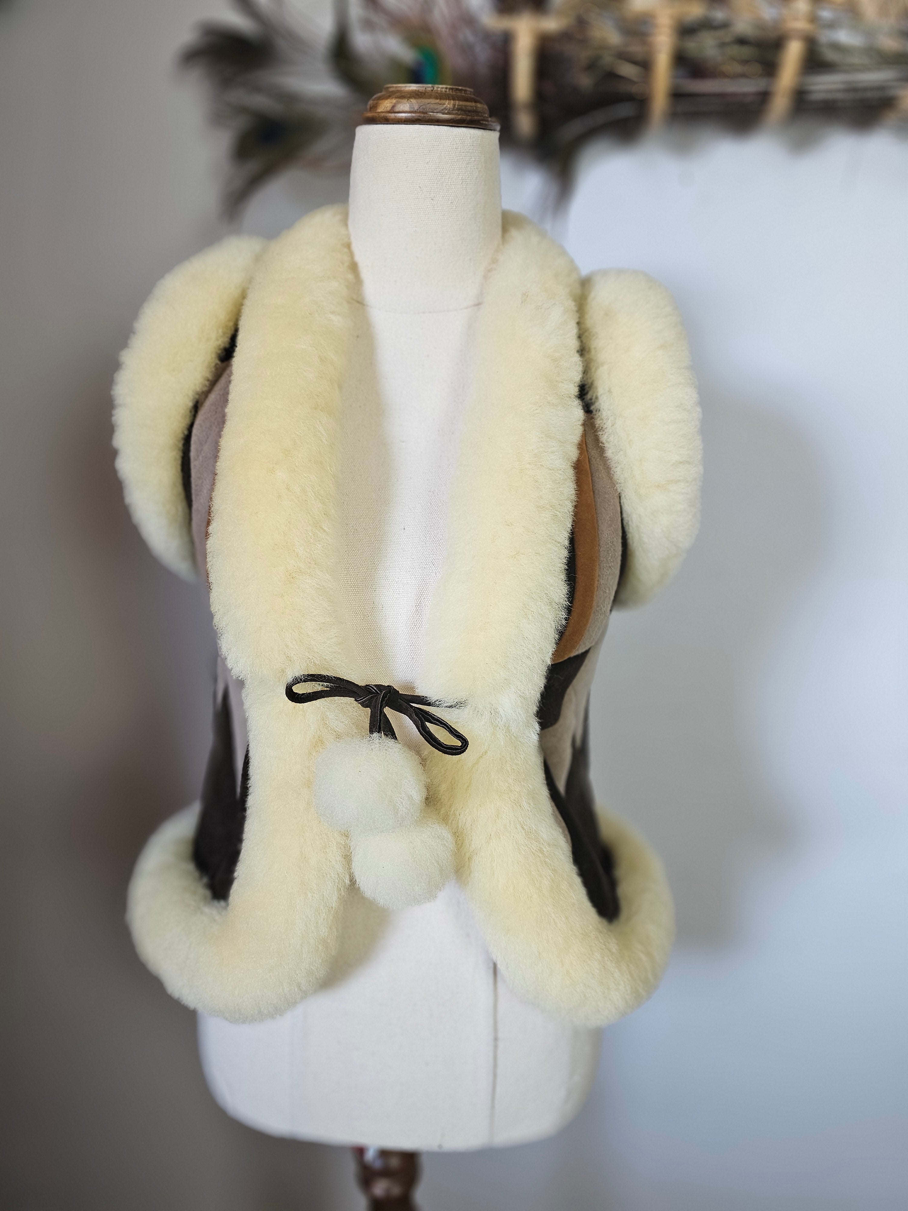 White shearling vest with fur trim on a mannequin against a neutral background